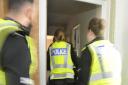 Officers enter the Cumnock property after the door is rammed open